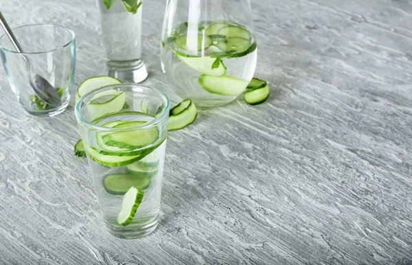 Glass of fresh cucumber water on light table