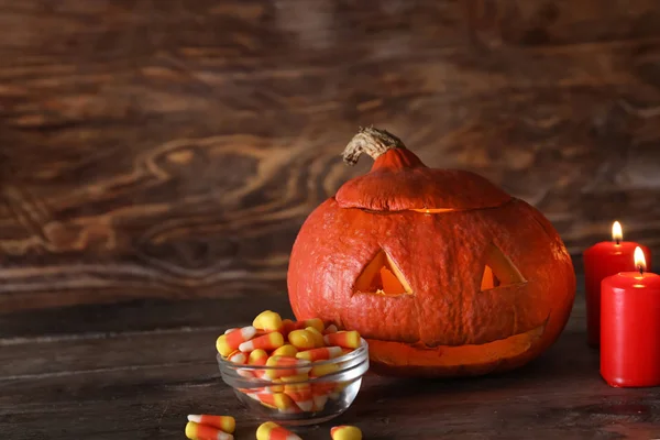 Halloween Kürbis Mit Bonbons Und Brennenden Kerzen Auf Holzgrund — Stockfoto