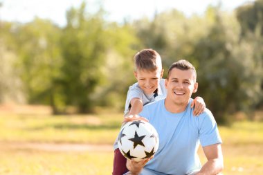 Küçük bir çocuk ve babası ile futbol topu açık havada