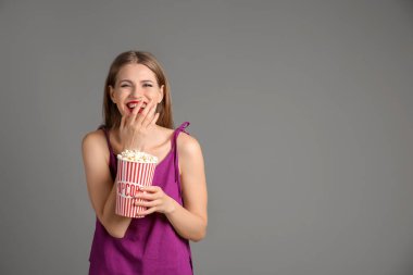 Gri arka plan üzerinde patlamış mısır fincan duygusal genç kadın