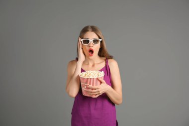 Patlamış mısır ve gri arka plan üzerinde 3d sinema gözlük fincan duygusal genç kadın