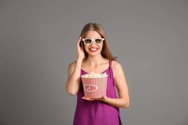 Patlamış mısır ve 3d sinema gözlük gri arka plan üzerine bir güzel genç kadın
