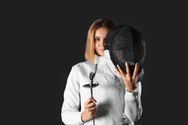 Koyu arka plan üzerinde genç kadın fencer