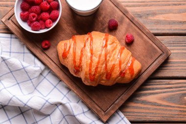 Ahşap tahta üzerinde frambuaz reçeli ile lezzetli kruvasan