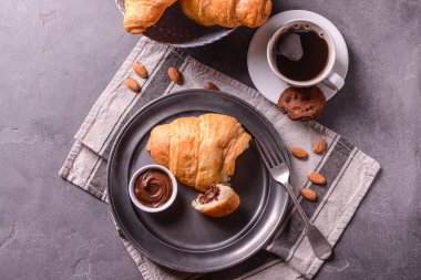 Çikolatalı hamur ve gri masada kahve ile lezzetli kruvasan