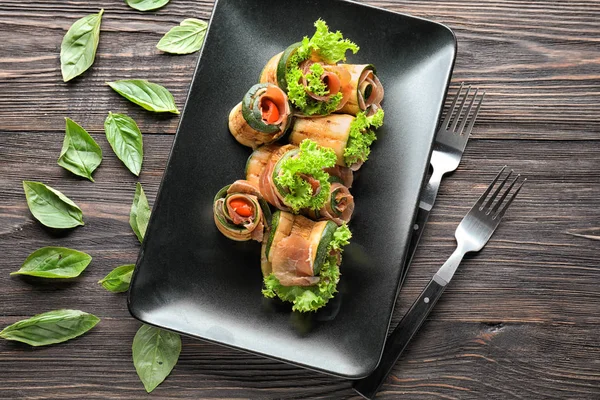 Tasty zucchini rolls with prosciutto on plate