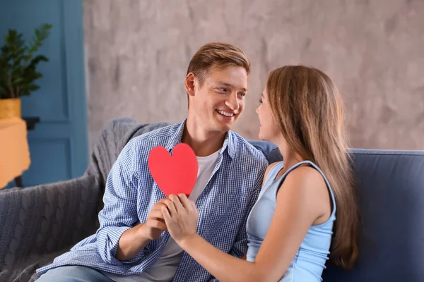 Feliz Pareja Joven Con Corazón Rojo Sentado Sofá Casa —  Fotos de Stock