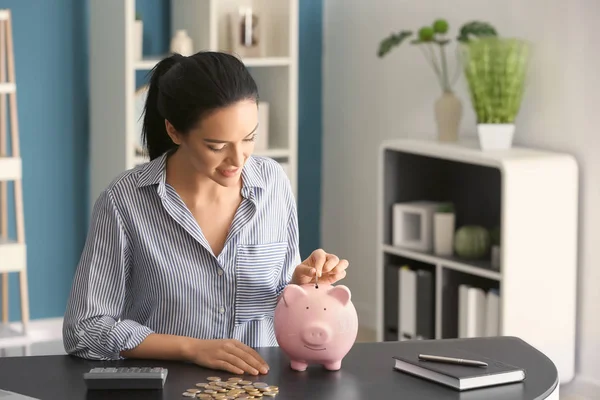 Mujer Joven Poniendo Dinero Alcancía Mesa —  Fotos de Stock