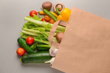 Kağıt torba gri arka plan üzerinde çeşitli taze sebze ile