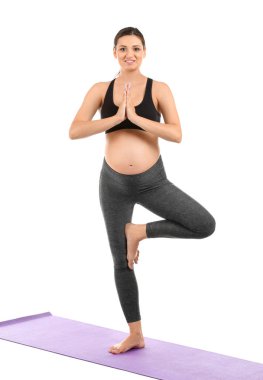 Genç hamile kadın beyaz arka planda yoga yapıyor.