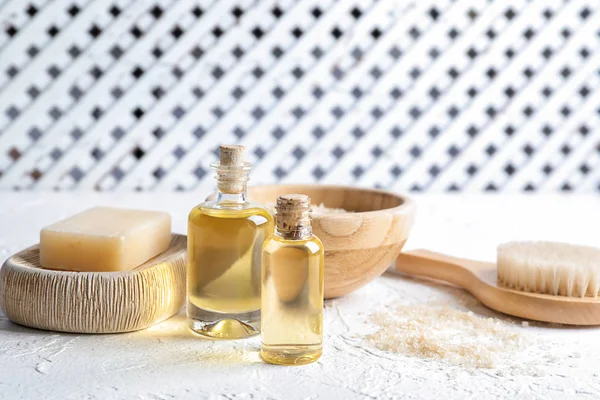 Bottles with essential oil and bath products and brush on white table