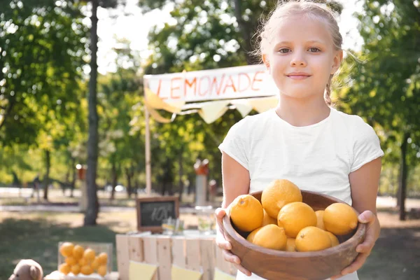 Liten Flicka Innehav Skål Med Mogna Citroner Nära Stativ Park — Stockfoto