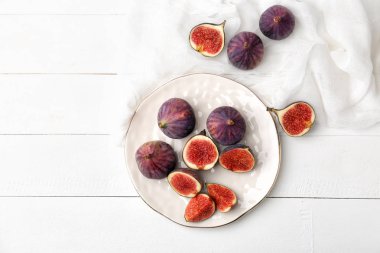 Beyaz ahşap masa üzerinde taze olgun incir ile plaka