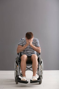 Tekerlekli sandalyeye mahkum gri duvara depresif genç adam