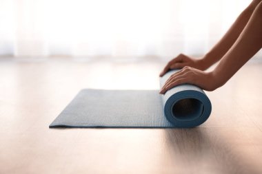 Genç kadın yoga mat katta haddeleme