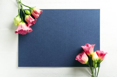 Güzel çiçek açan çiçekler ve beyaz masada boş oyun kağıdı