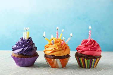 Renk arka plan üzerinde mum ile lezzetli Doğum günü cupcakes