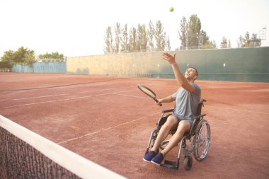 Tekerlekli sandalyede tenis oynayan genç adam.