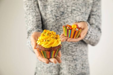 Leziz cupcake tutarak ve açık renkli, tatlı şekerler fincanla pişirme kadın