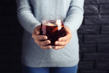 Lezzetli bardak sıcak tutan kadın mulled şarap tuğla duvar arka plan üzerinde