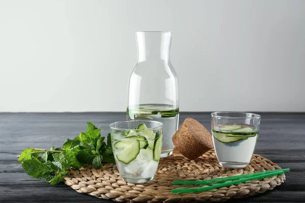 Glassware of fresh cucumber water on wicker mat