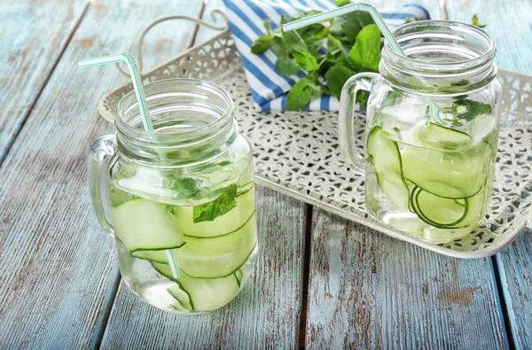 Mason jars of fresh cucumber water on wooden table