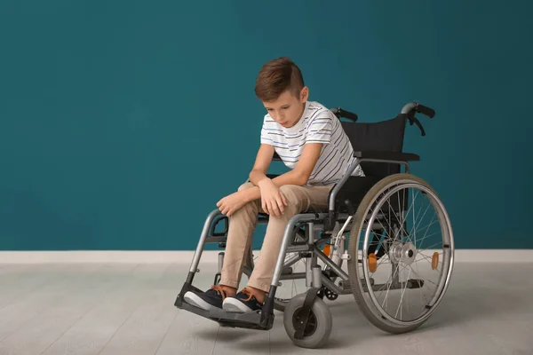 色の壁に車椅子で落ち込んでいる少年 — ストック写真