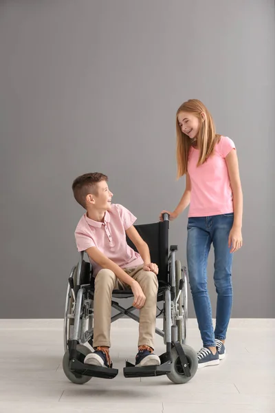 男孩在轮椅和他的妹妹反对灰色墙 — 图库照片