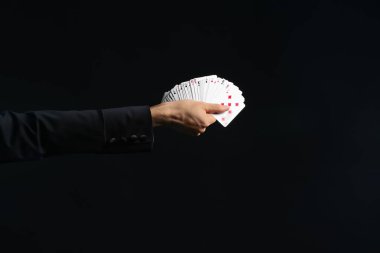 Hand of magician holding cards on dark background clipart