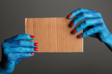 Boş kartı gri arka plan üzerinde tutan canavar