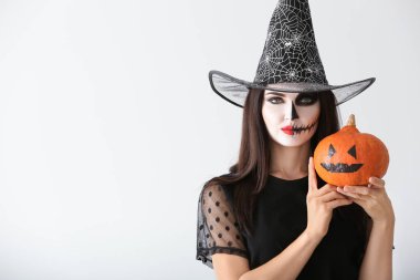 Cadı olarak ışık arka plan üzerinde kabak ile Cadılar Bayramı için giymiş kadın güzel