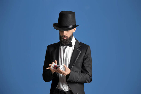 Фокусник показывает фокусы с карточками на цветном фоне
