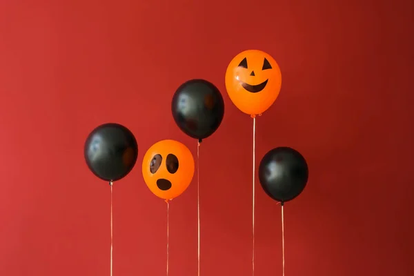 Creative balloons for Halloween party on color background