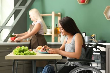Tekerlekli sandalye evde yemek içinde genç kadın