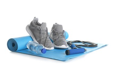Yoga mat spor ayakkabı, beyaz arka plan üzerinde atlama ipi ve şişe suyu ile