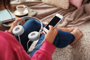 Akıllı telefon ve kulaklık katta evde oturan kadın ile