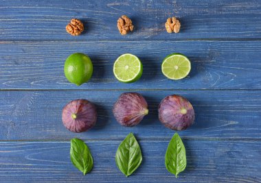 Olgun incir, kireç ve renk ahşap arka plan üzerinde fesleğen ile kompozisyon