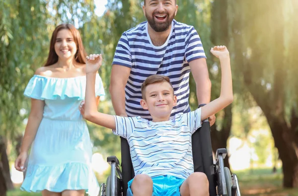 Teenage boy in wheelchair with his family walking outdoors