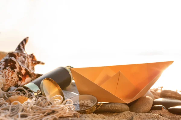 Origami boat with travel accessories on sand