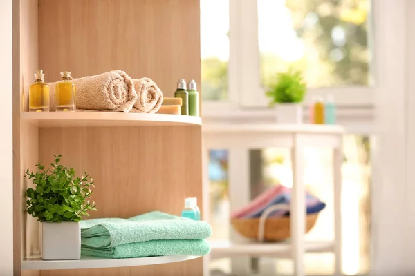 Clean towels and cosmetics on shelves in bathroom