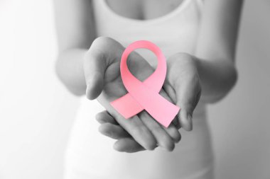 Açık renkli, tatlı pembe kurdele tutan kadın. Meme kanseri kavramı