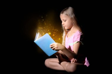 Sevimli küçük kız koyu arka plan üzerinde sihirli kitap okuma