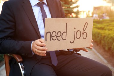 Açık havada office koltukta otururken karton ile metin gerek iş parçası tutan işadamı