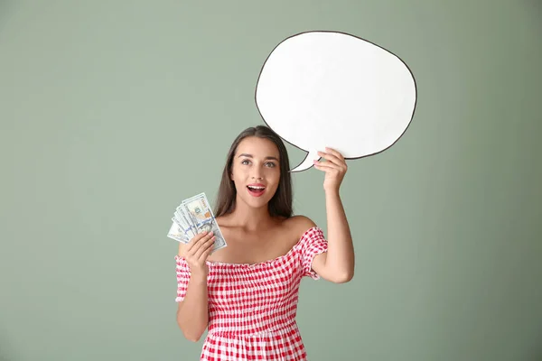 Emotional young woman with money and blank speech bubble on color background