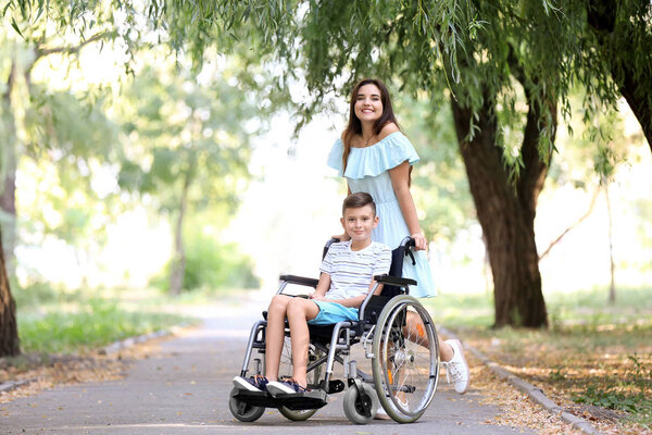Teenage boy in wheelchair with his mother outdoors