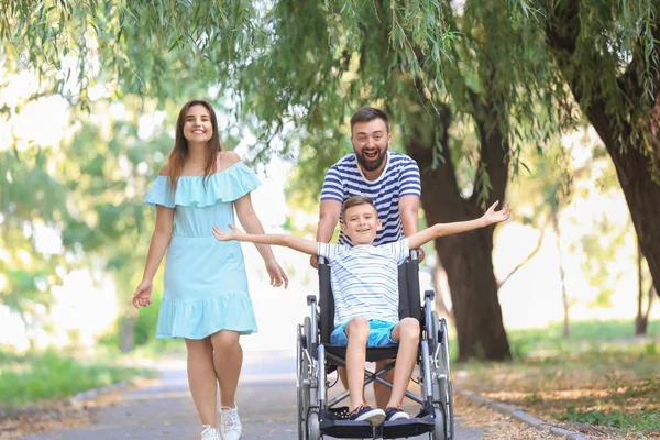 Teenage boy in wheelchair with his family walking outdoors