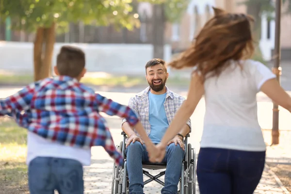 在轮椅的年轻人玩与他的家庭户外 — 图库照片