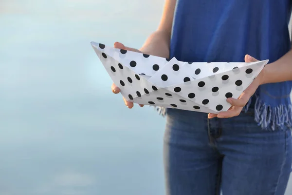Woman holding origami boat outdoors
