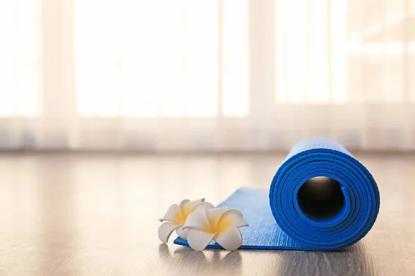 Rolled yoga mat and flowers on floor