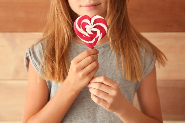 Niedliches Kleines Mädchen Mit Herzförmigem Lutscher Auf Hölzernem Hintergrund Nahaufnahme — Stockfoto